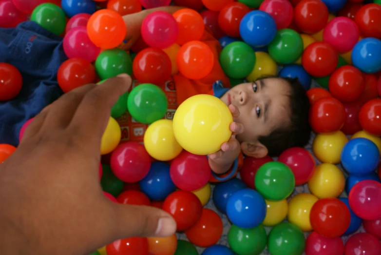 a baby playing with balloons in a ball pit