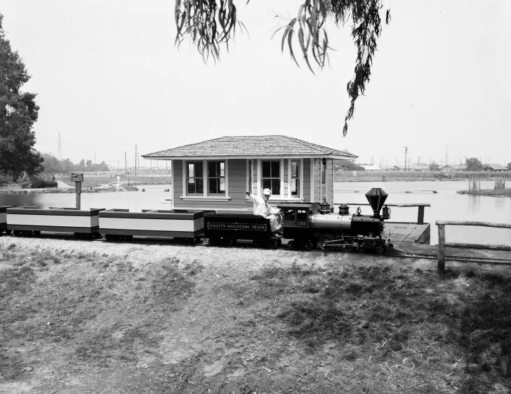 an old pograph of a house with a train traveling by