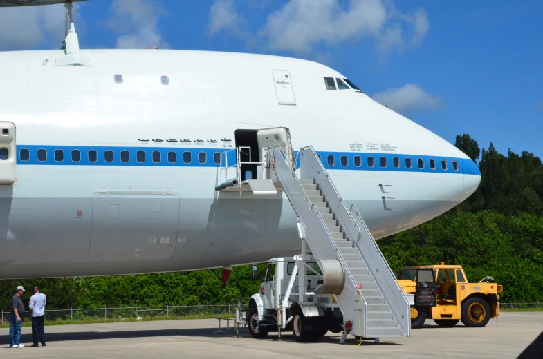 people are waiting around a ladder to reach the back of an airplane