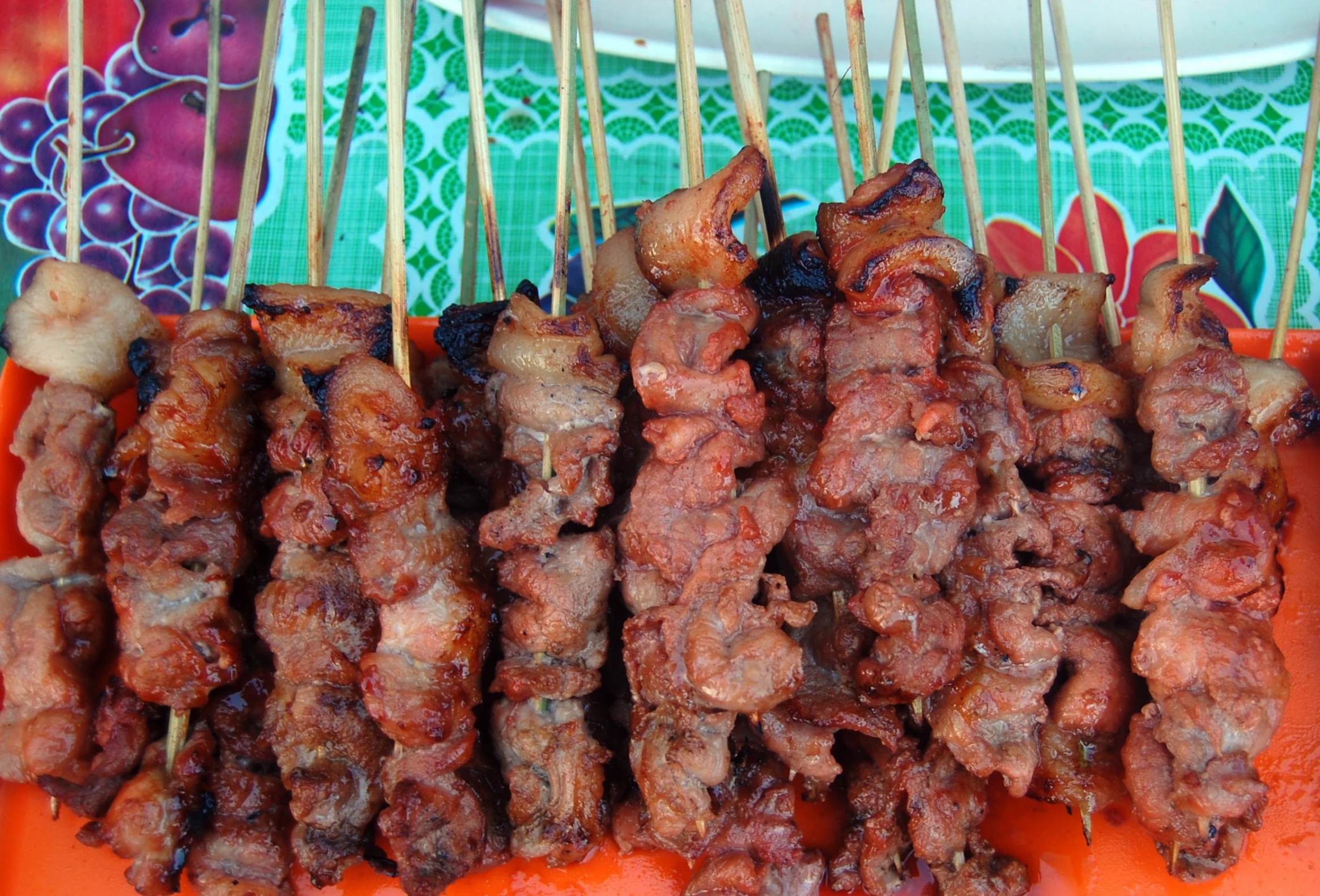 several meat skewers resting on a bright orange tray