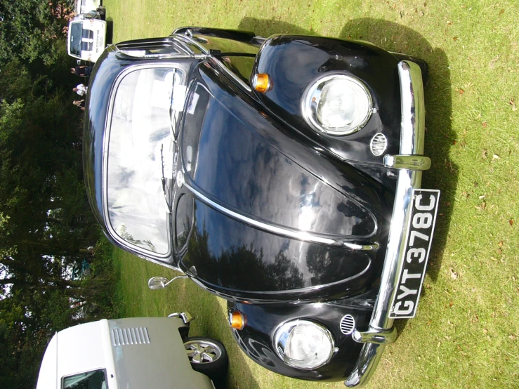 an old fashioned black car with a vw bug emblem