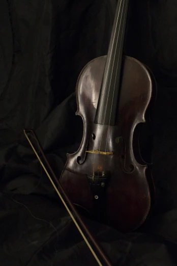 a violin resting on a bed with a cane