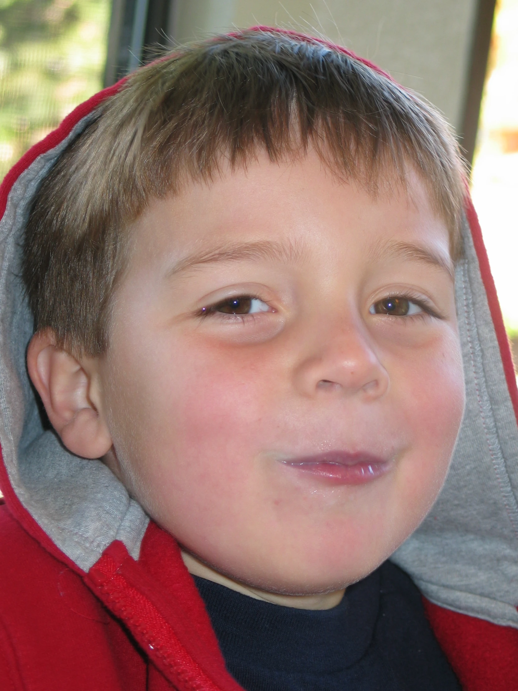 the  smiles as he wears a red hoodie