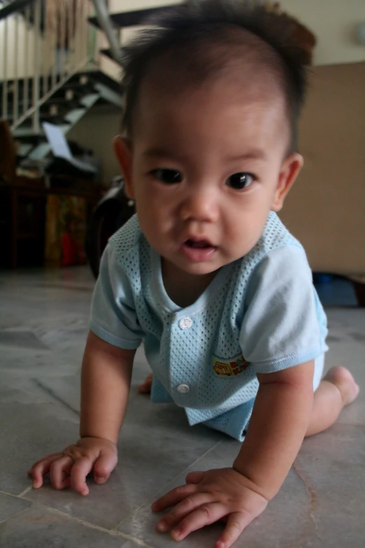 an asian baby crawling on the floor and looking at the camera