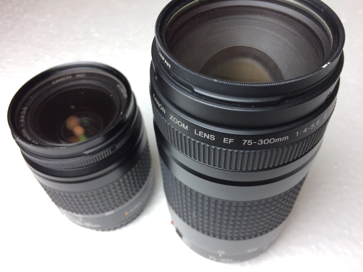 two empty camera lens bottles are stacked on a table