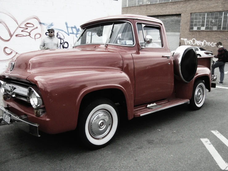 an old classic red pickup truck parked in front of a white building