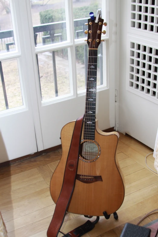 a small wooden guitar stands in front of windows