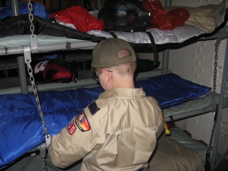 man in khaki jacket, helmet and glasses working on some bunk beds