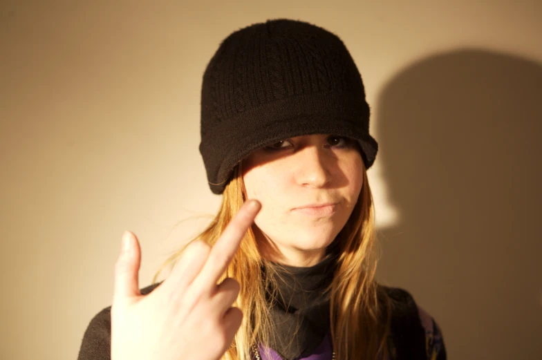 a girl with long hair in a beanie pointing to the side