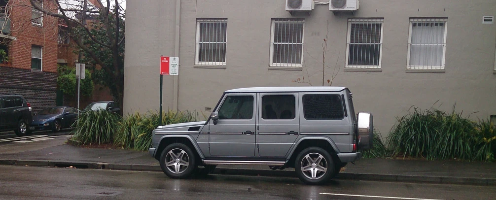 a grey mercedes benz benz benz - benz is parked in front of an apartment building