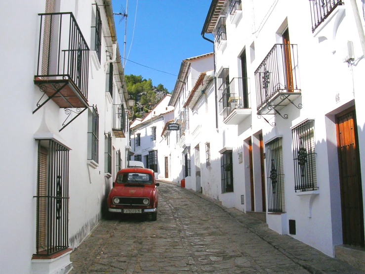 a red car parked on the road between two white houses