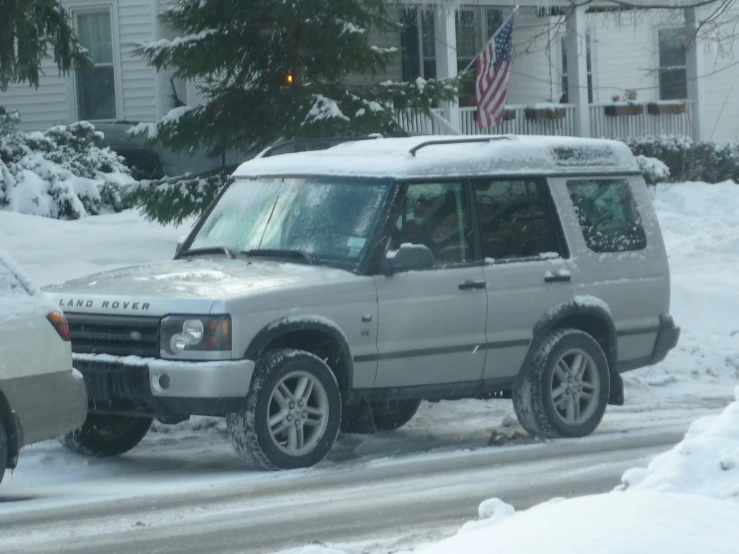 a suv drives in the snow next to a house