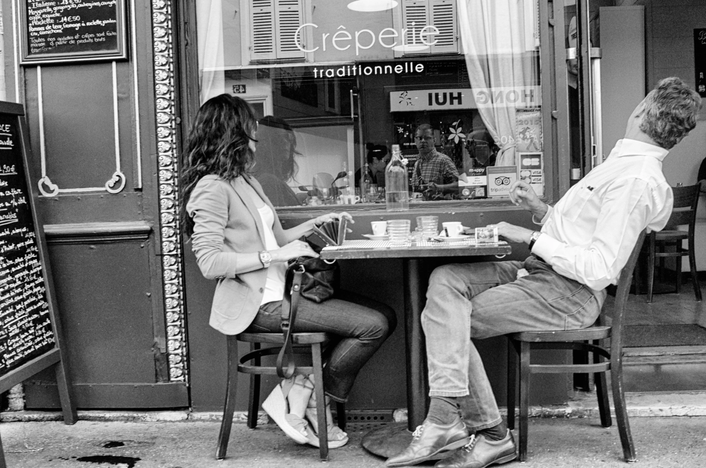 a couple sitting at a table playing chess in front of a shop