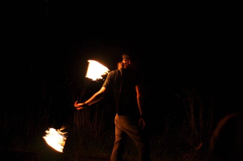 the young man is holding fire to burn his sticks