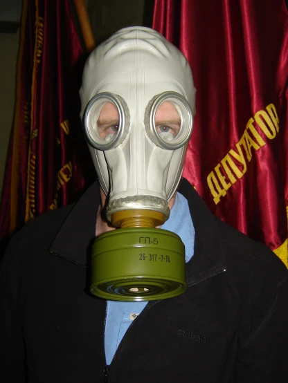 man wearing gas mask and goggles near a curtain