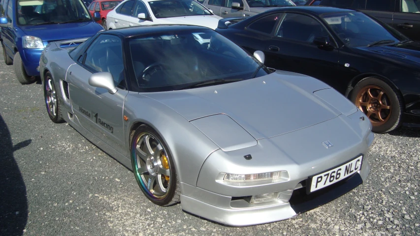 the silver sports car is parked next to other cars