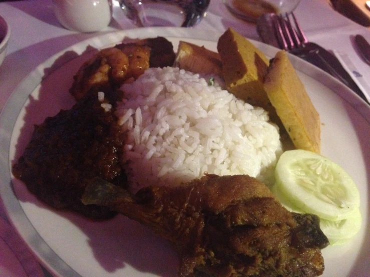 some sort of chicken dish with rice and a side of cucumber