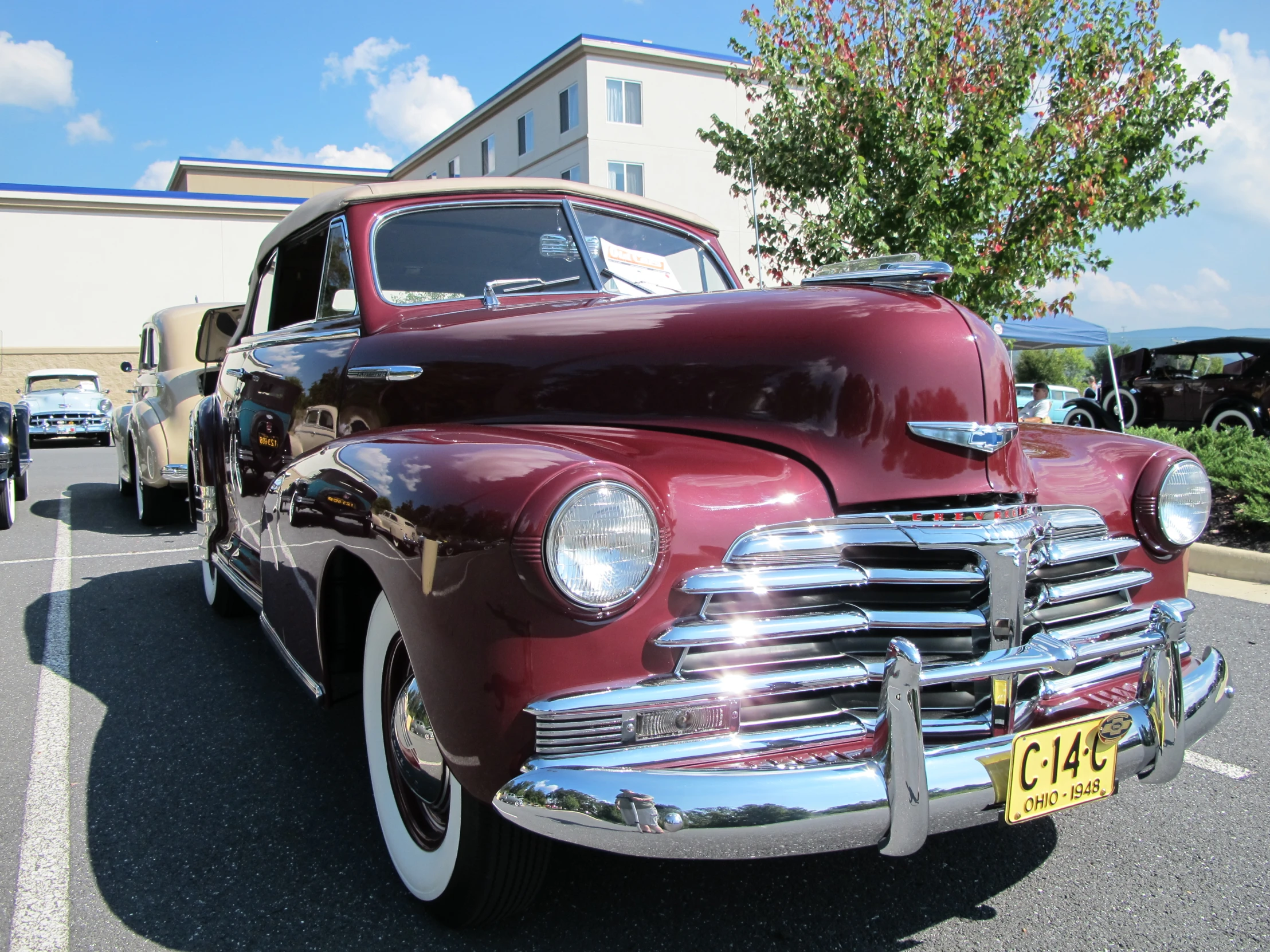 an old maroon car is parked next to a building