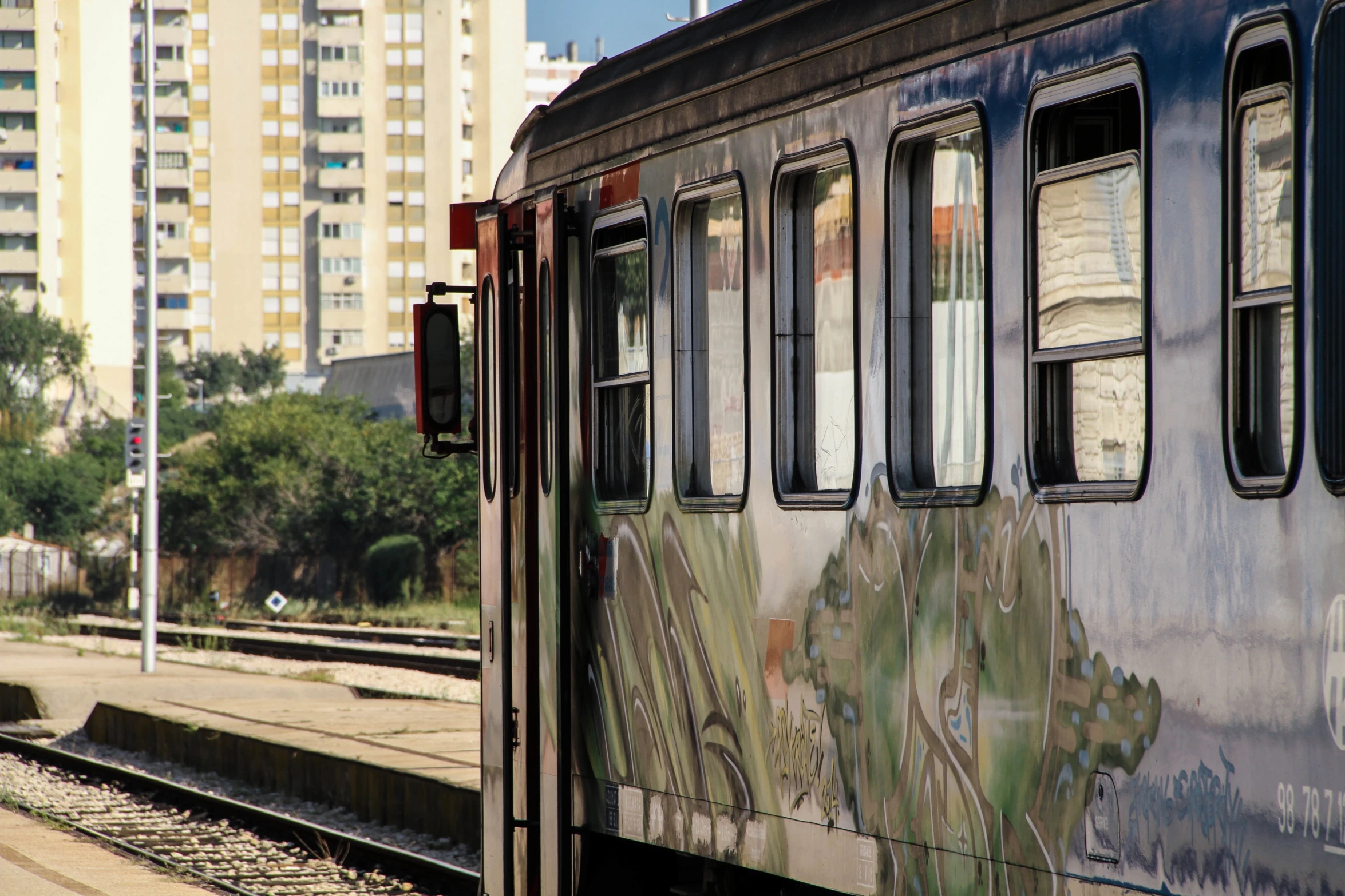 the reflection of the trees and buildings is in this window on the train