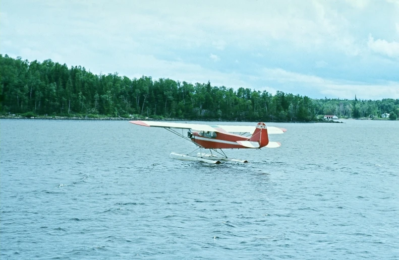 a sea plane flying over the ocean with trees in the background