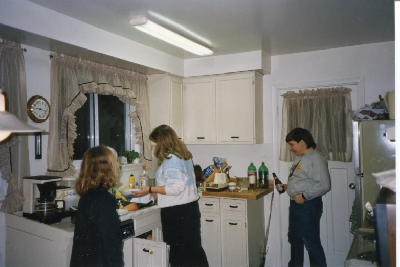 people in a kitchen with white cabinets and counters