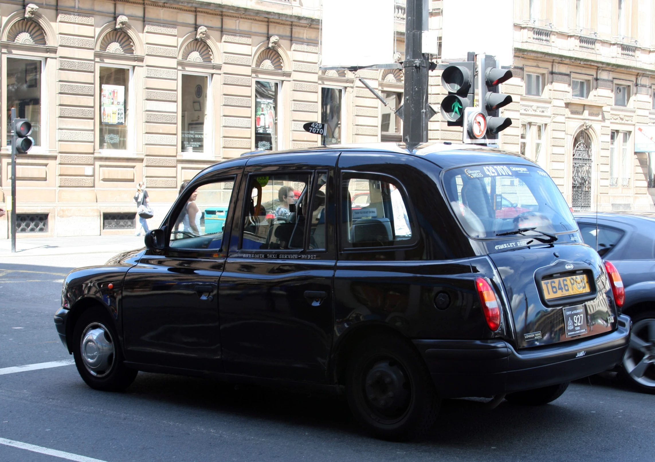 a cab in front of two buildings that have a traffic light above it