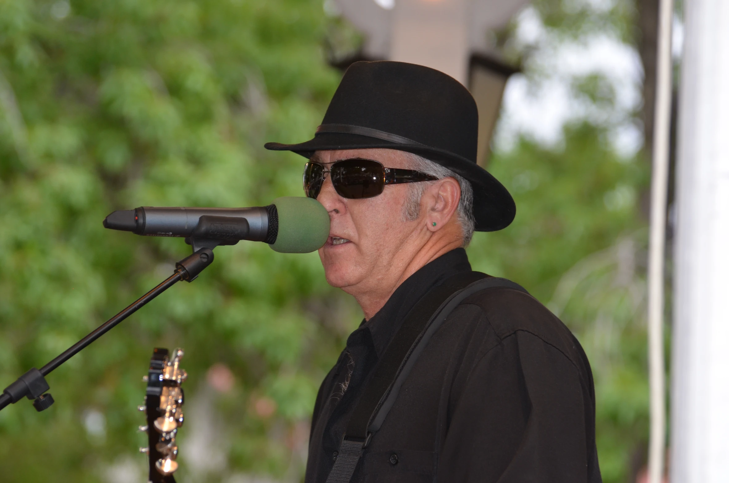 a man singing into a microphone, wearing sunglasses