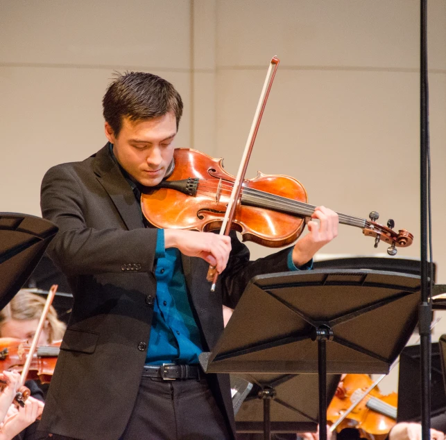 a man with his violin in front of the orchestra