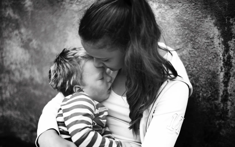 mother with child posing for a picture in front of concrete wall