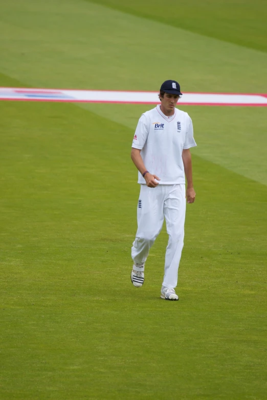 a man in white clothes standing on grass with tennis racket