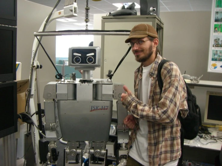 a man holding his hands up in a room with a robot on it