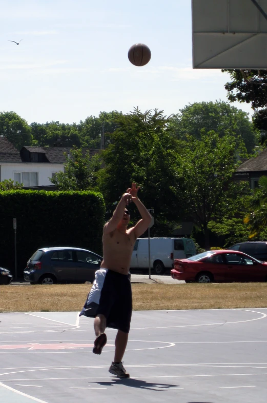 a shirtless man is reaching up to hit a basketball