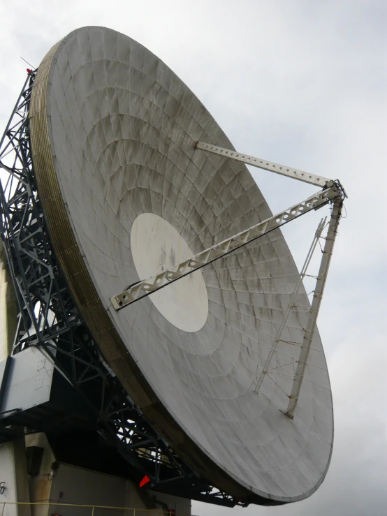 a very large satellite dish outside on a cloudy day