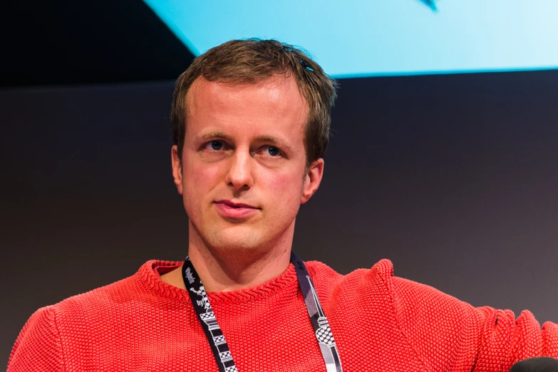 the man is wearing a red shirt while holding a lanyard