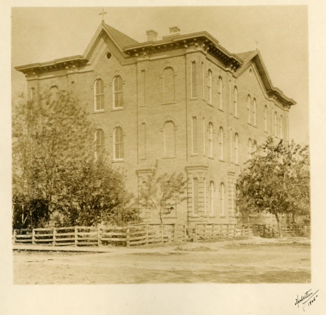 the old building is sitting next to two trees