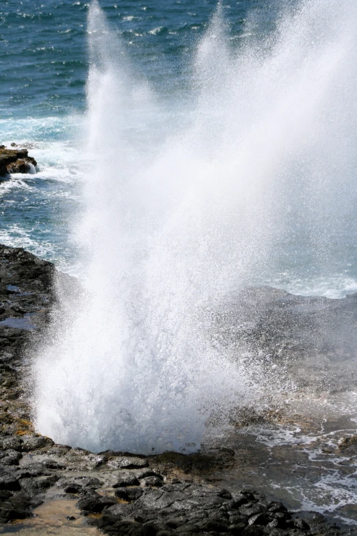 a blow coming out from the ocean onto rocks