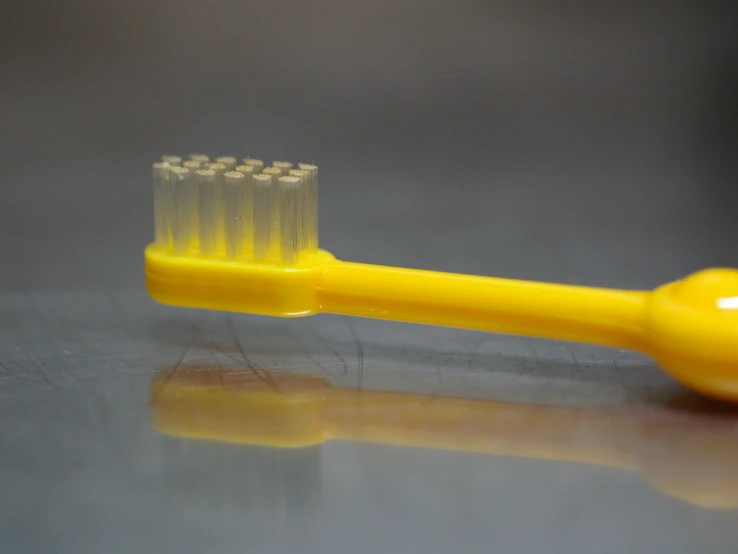 a close up po of an orange toothbrush with five teeth