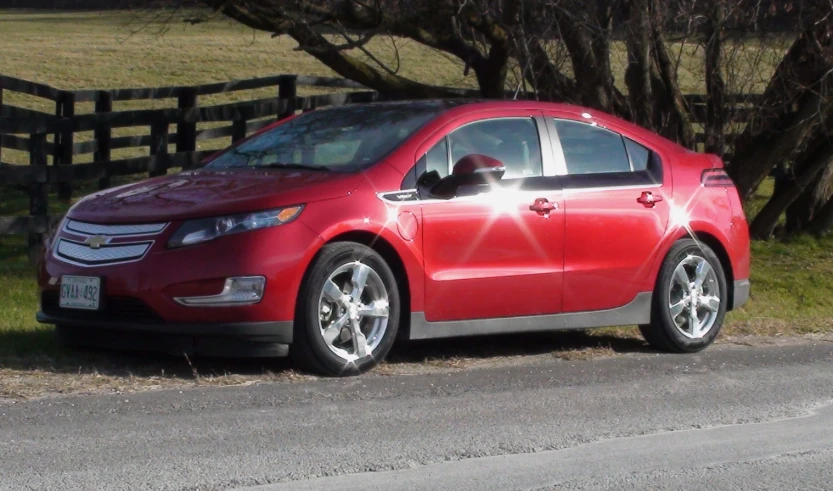 a red car parked next to a brown fence