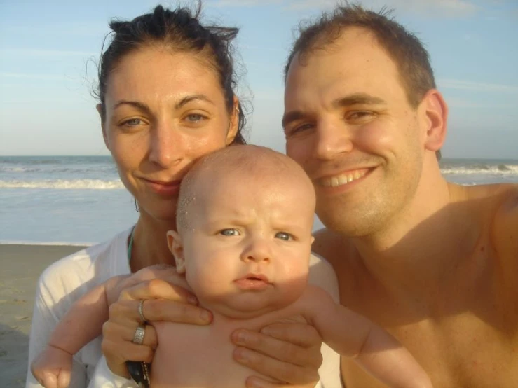 an image of a woman holding her baby by the ocean