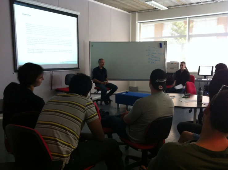 a group of people sitting in front of a screen