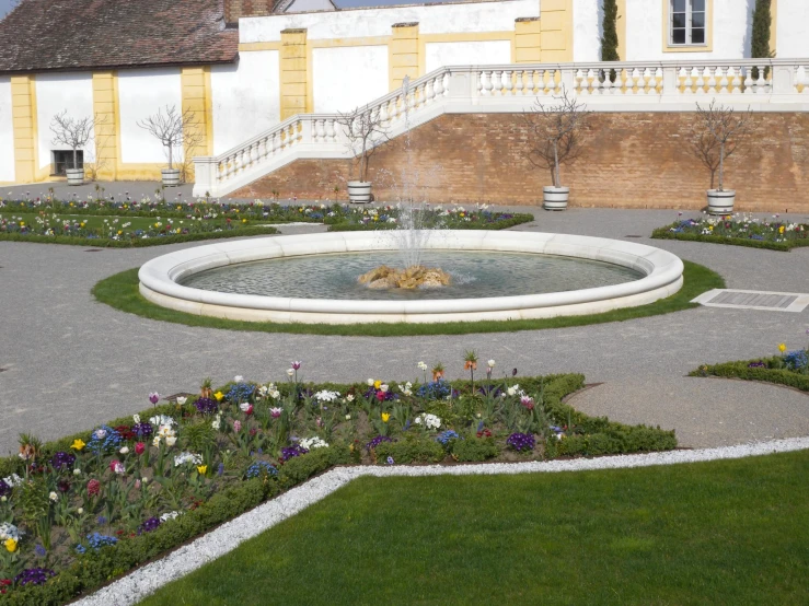 a fountain in a flower garden with a lion laying across the fountain