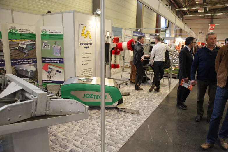 people are standing near a model of a green and white boat