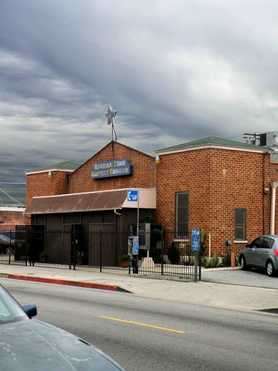 a brown building with a fence and parked cars