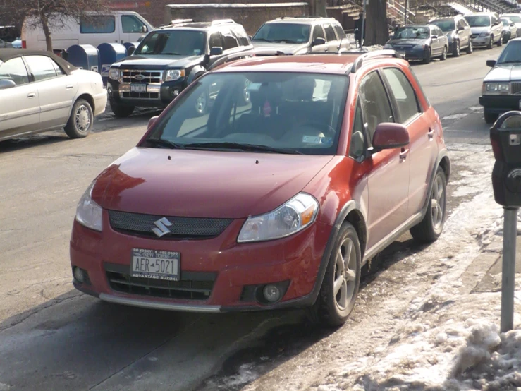 small red compact parked next to parking meter