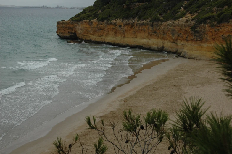 a large cliff next to a sandy beach