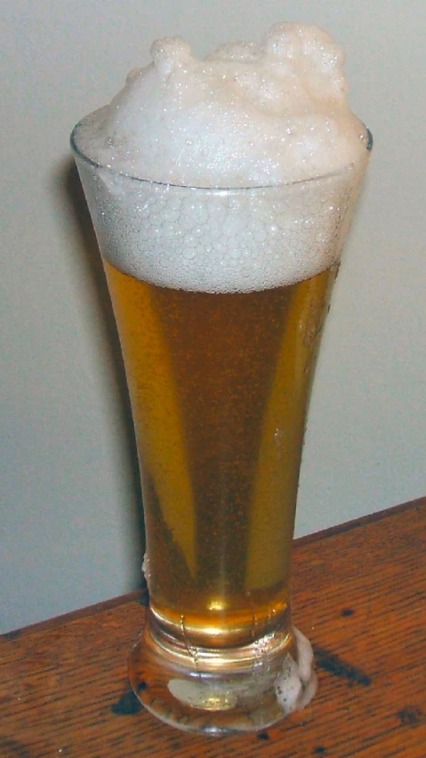 a glass of light beer on a wooden table