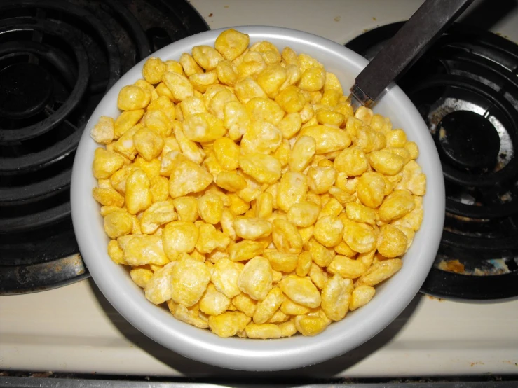 a white bowl filled with corn kernels on top of a stove