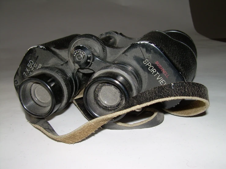 the worn old pair of binoculars are sitting on the table