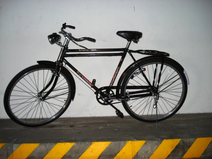 a close - up of a black bicycle propped against a wall
