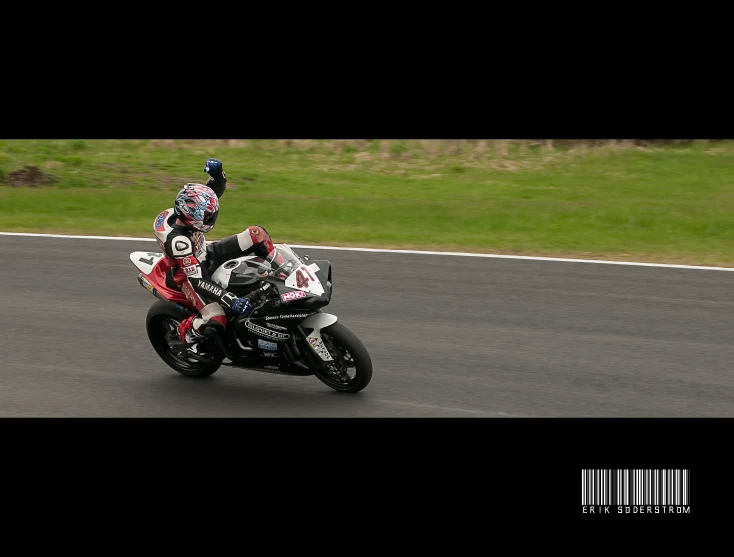 a man on a motorcycle with a red and black jacket is making a right turn